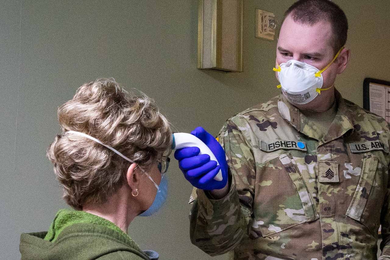 Guardsman takes a health care worker’s temperature.