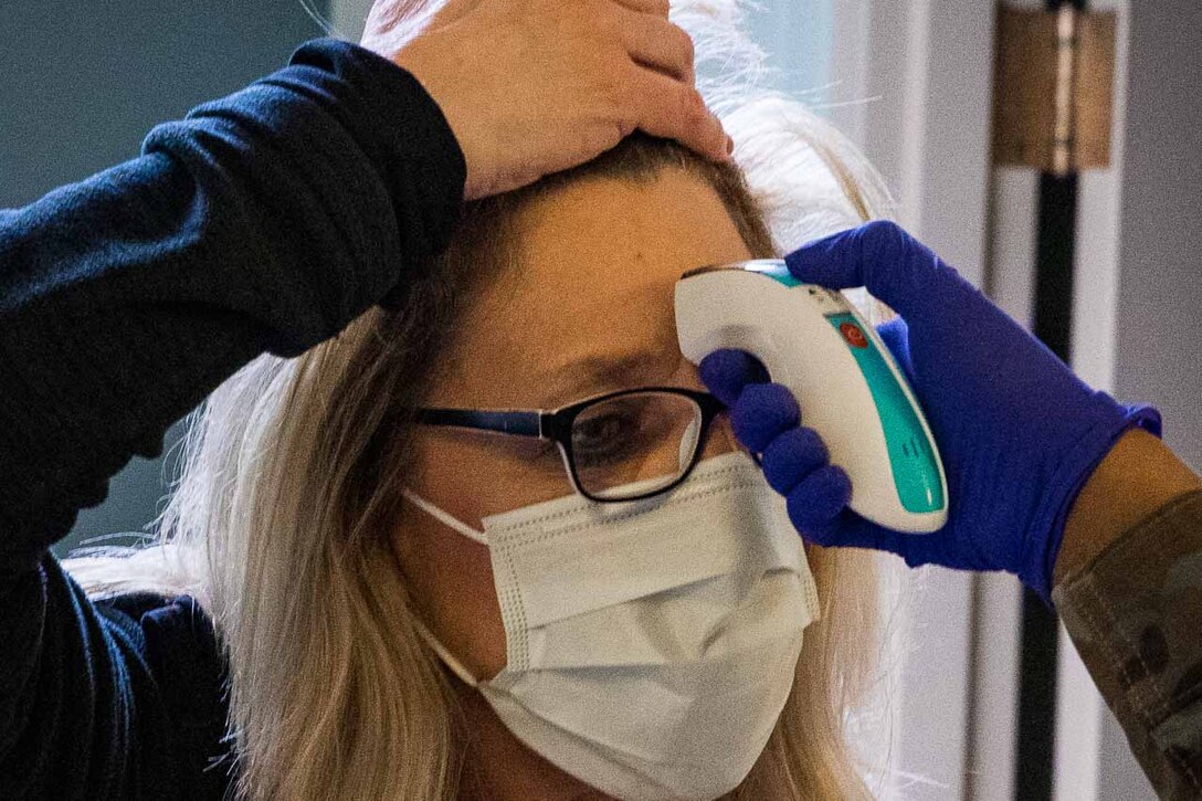 A health care worker getting her temperature taken before starting her shift.
