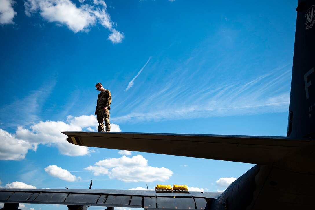 Photo of Airman examining the tail of an HC-130J Combat King II.
