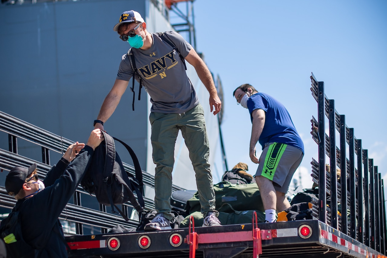 Sailors loading bags into the back of a truck.