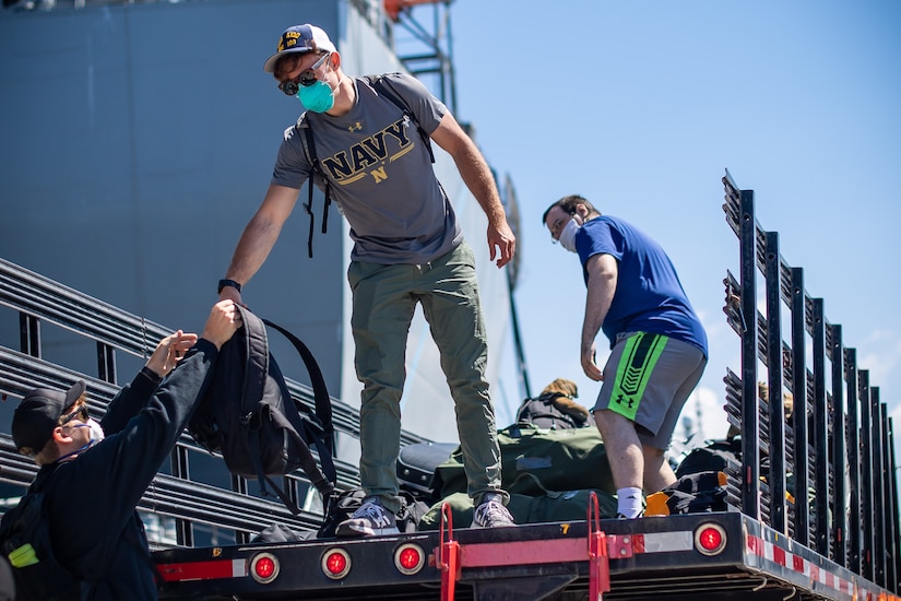 Sailors loading bags into the back of a truck.