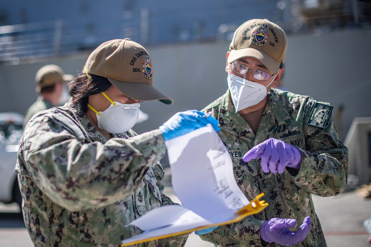 Sailors reading over a muster sheet.