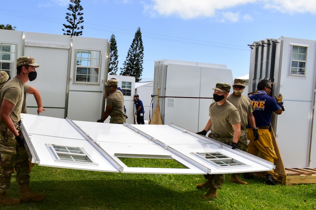 Service members and civilians construct temporary shelters for residents.