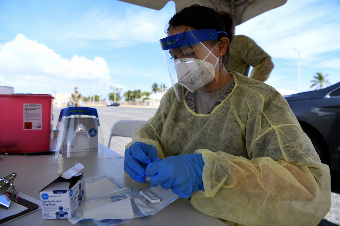 An  airman in personal protective equipment conducts a lab test.