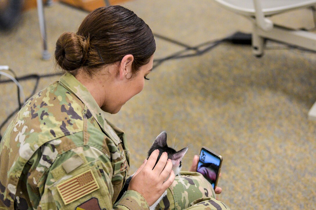 An airman holds a cat while video-chatting.