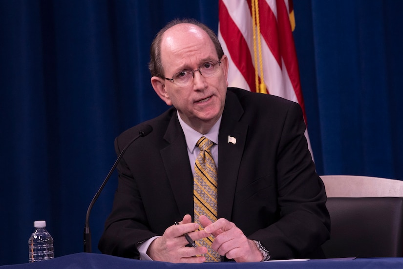 A civilian speaks at a table.