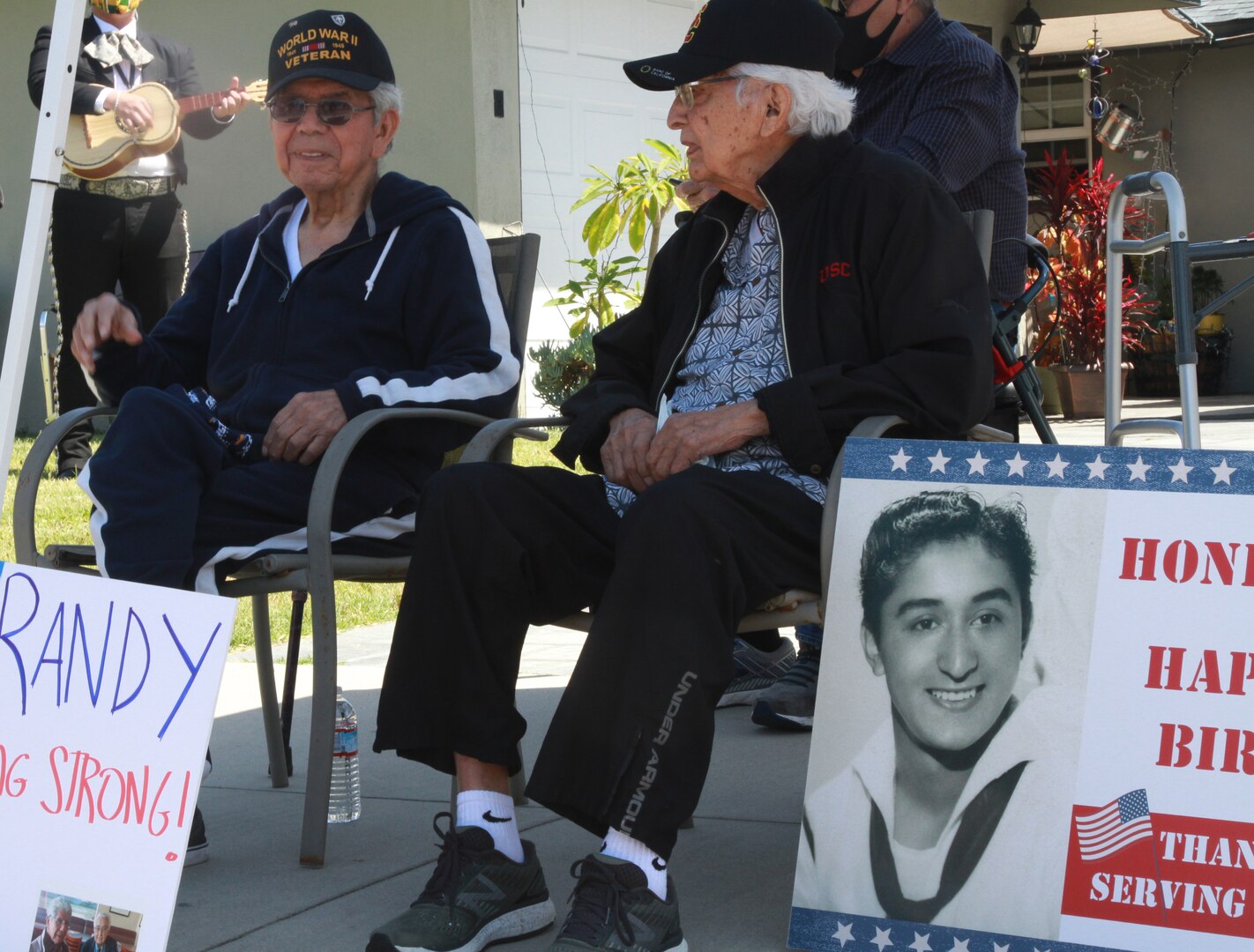 U.S. Army veteran Randy Zepeda Fernandez, left, and U.S. Coast Guard veteran Sal Guzman, right, listen to a mariachi band play ‘Happy Birthday’ during a social distancing double birthday celebration in Whittier, California, May 24, 2020, during the COVID-19 pandemic. The event was coordinated by the Los Angeles County Sheriff’s Department to honor the World War II veterans' 96th and 97th birthdays.