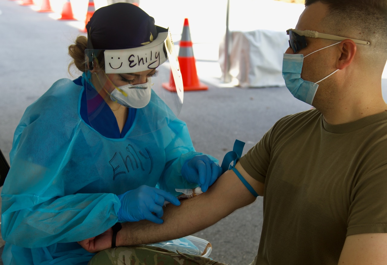 A nurse draws blood from a soldier.