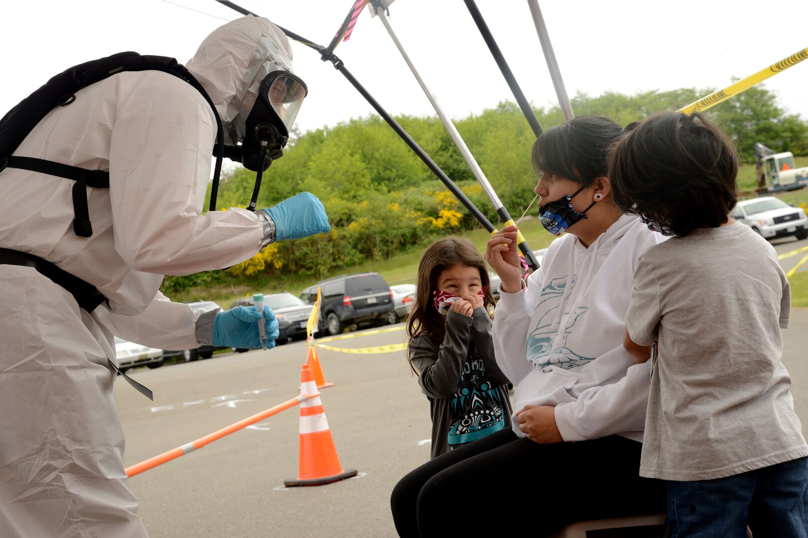 Senior Airman Nathan Kepple, left, a medic assigned to the 141st Air Refueling Wing Medical Group, tests Lia Frenchman for COVID-19 as her children watch at a site established by the Washington National Guard on the Quinault Indian Nation Reservation, Taholah, Wash., May 20, 2020.