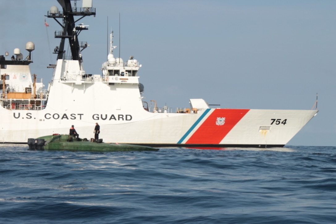 A low-profile go-fast vessel is shown next to the Coast Guard Cutter James.