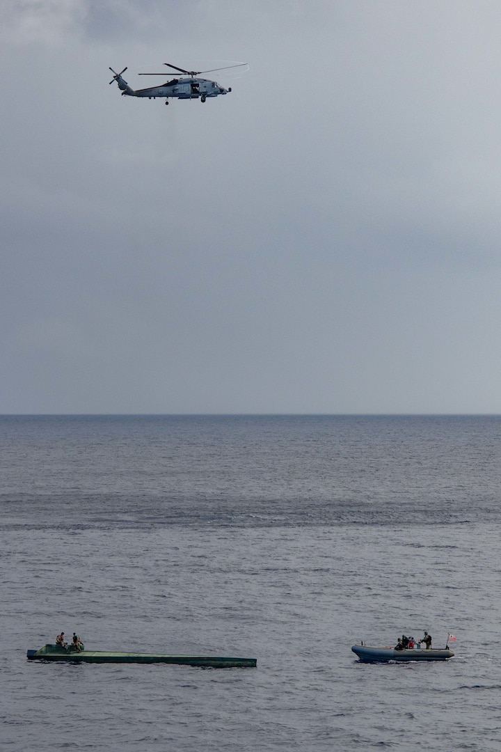 U.S. Navy and Coast Guard crews in a boat approach a suspected drug trafficking vessel.