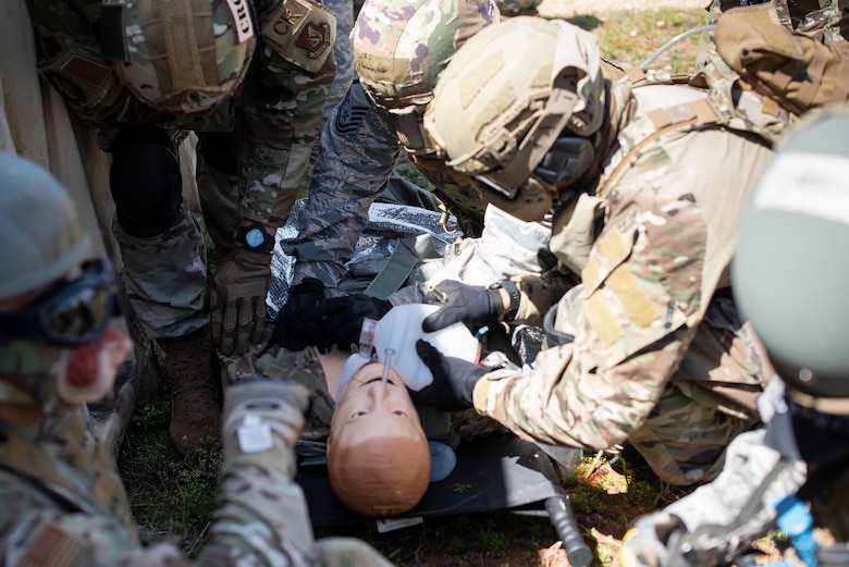 Students of a Tactical Combat Casualty Care class provide breaths to a simulated critically injured patient using a bag valve mask and prepare to perform needle decompression during the “care under fire” portion of the class, May 13, 2020 at Andersen Air Force Base, Guam.