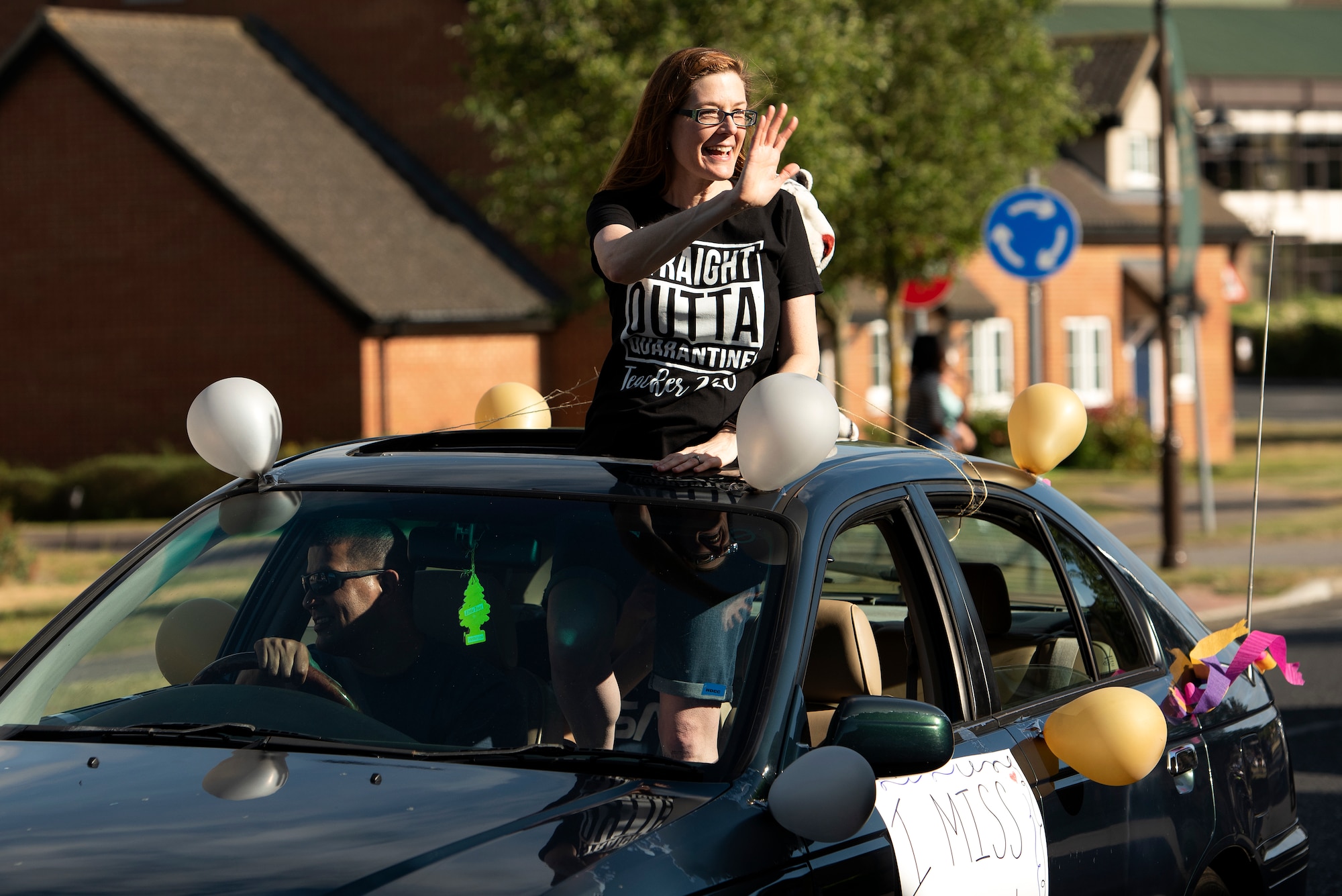 A Liberty Intermediate School teacher waves to students during a parade in Liberty Village at Royal Air Force Lakenheath, England, May 26, 2020. The parade was held as an end of school year "summer sendoff" for students, faculty, staff and family members. (U.S. Air Force photo by Airman 1st Class Jessi Monte)