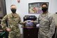 Two Airmen stand together holding a face mask they made using a 3-D printer.