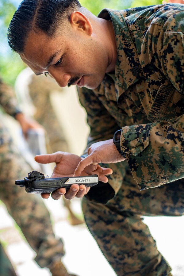 Sgt. Justin Cortez, a civil affairs specialist with Special Purpose Marine Air-Ground Task Force - Southern Command, receives a field radio during land navigation training at Camp Lejeune, North Carolina, May 4, 2020. Land navigation consists of being able to use skills that can help one traverse through unfamiliar terrain by foot or in a vehicle. Marines and Sailors with SPMAGTF-SC are conducting a variety of pre-deployment training events and qualifications to enhance crisis response readiness. These events assist the Marines and Sailors with providing humanitarian aid assistance and engineering projects alongside partner nation military forces in Latin America and the Caribbean. Cortez is a native of Miami, Florida. (U.S. Marine Corps photo by Sgt. Andy O. Martinez)