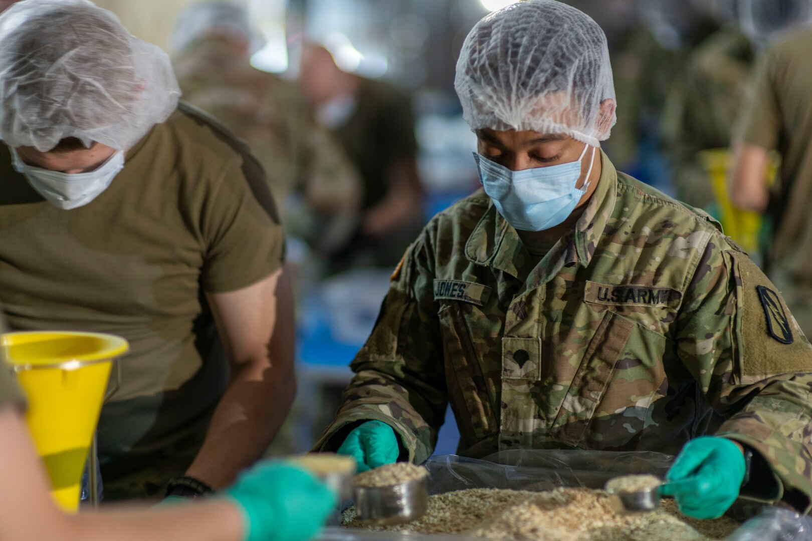 Spc. Dondi Jones, Company A, 2nd Combined Arms Battalion, 137th Infantry Regiment, measures out food in a boxed-meal assembly line operation in Leawood, Kansas, May 1, 2020. Kansas National Guard Soldiers, through The Outreach Program, packaged more than 2 million meals to be distributed to food banks across Kansas.
