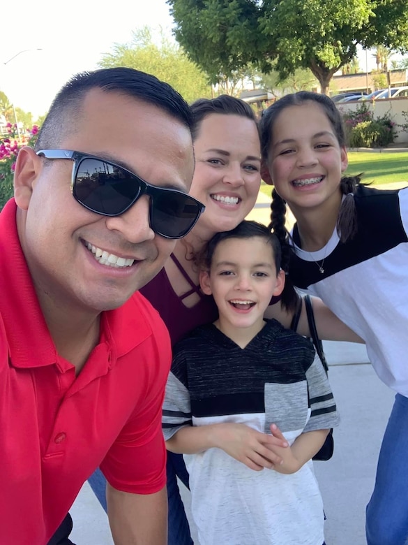 Man in red shirt with a lady and two young girls in black and white shirts.