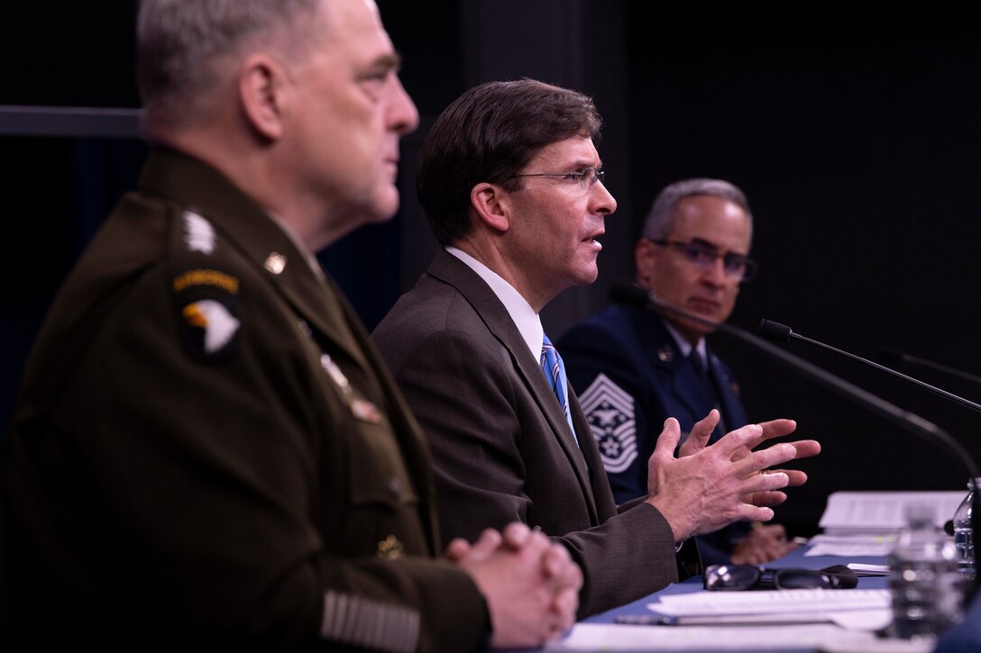 Three defense leaders sit behind a long table at a briefing.
