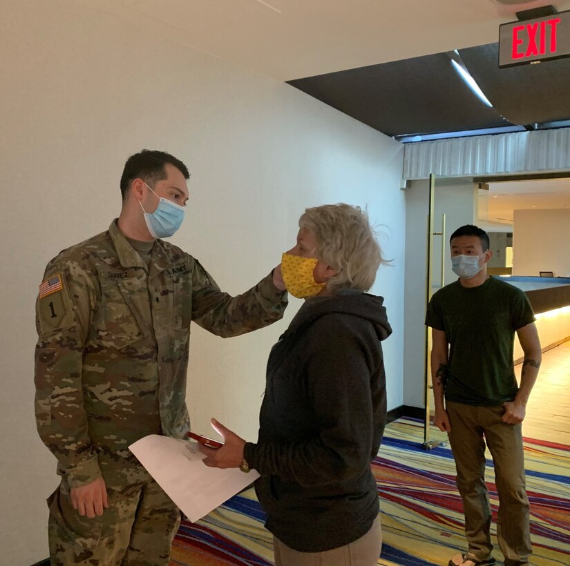 A soldier takes another soldier’s temperature.