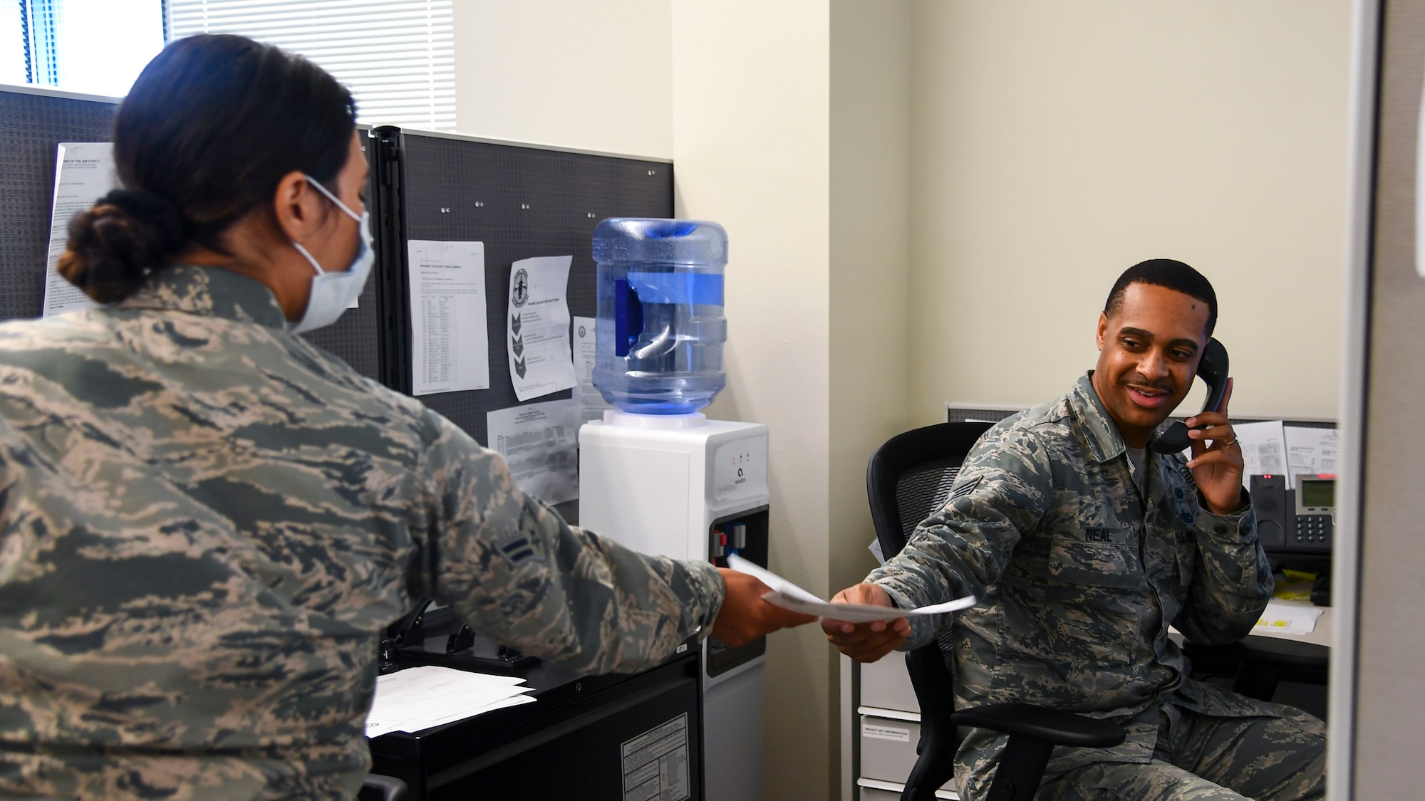 Staff Sergeant LeWillie Neal, 2nd Force Support Squadron NCO in charge of outbound assignments, hands off paperwork to a member of the outbound assignments team at Barksdale Air Force Base, La., May 21, 2020. The outbound assignments team has practiced innovation in the midst of COVID-19 in order to complete their workload. (U.S. Air Force photo by Senior Airman Christina Rios)