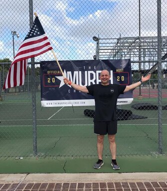 U.S. Air Force Col. Andres Nazario, 17th Training Wing commander, holds an American flag after completing the Murph Challenge on the pad near the Mathis Fitness Center, May 25, 2020.  Goodfellow had nearly 100 social-distancing participants on site and virtually. (Courtesy photo)