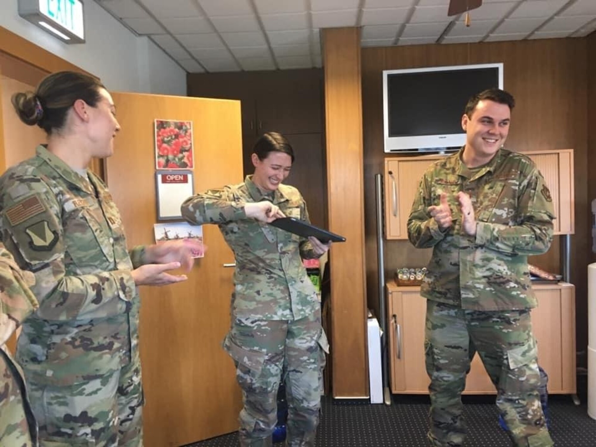 .S. Air Force Staff. Sgt. Kirsten Brandes, 86th Airlift Wing noncommissioned officer in charge of media, (center) reacts to receiving a coin from Brig. Gen. Mark R. August, 86th AW commander at Ramstein Air Base, Germany, May 21, 2020.