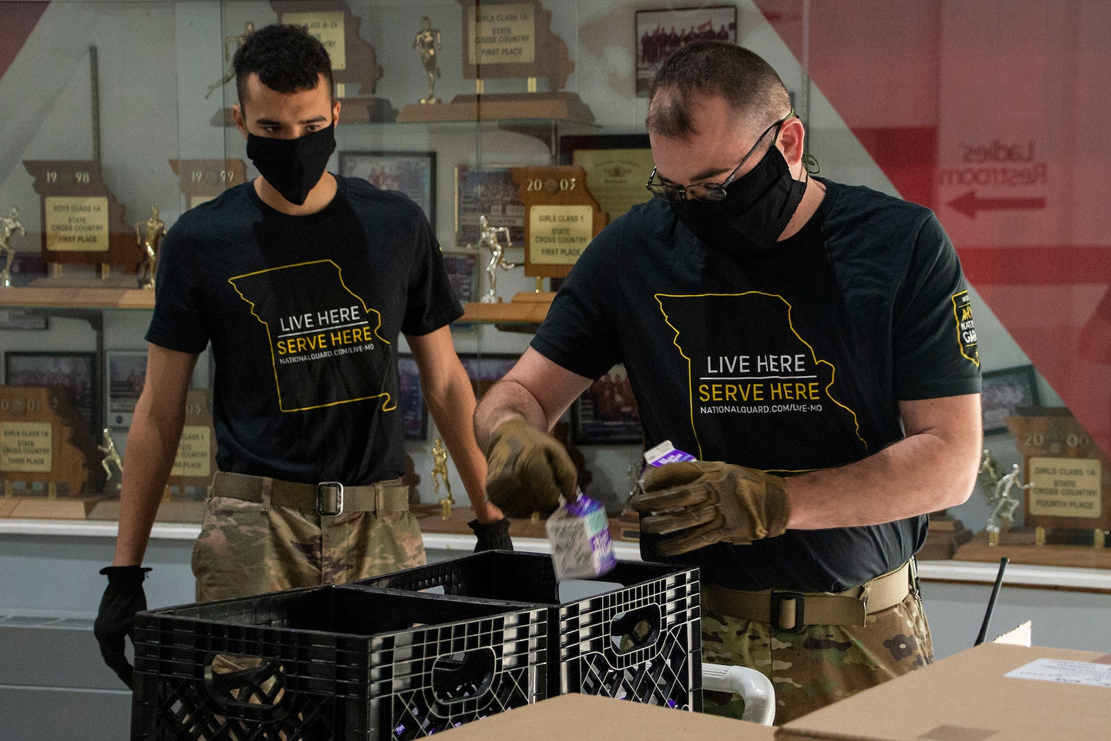 Spc. Ross Schlichting, left, and Staff Sgt. Vernon Long, with the 1221st Transport Company, Missouri National Guard, pack school lunches for delivery April 27, 2020, at Osage County R-II School, Linn, Missouri. Nearly 200 Guardsmen are assisting schools with distribution and delivery of food to students in communities across the state as part of the state’s response to the COVID-19 pandemic.