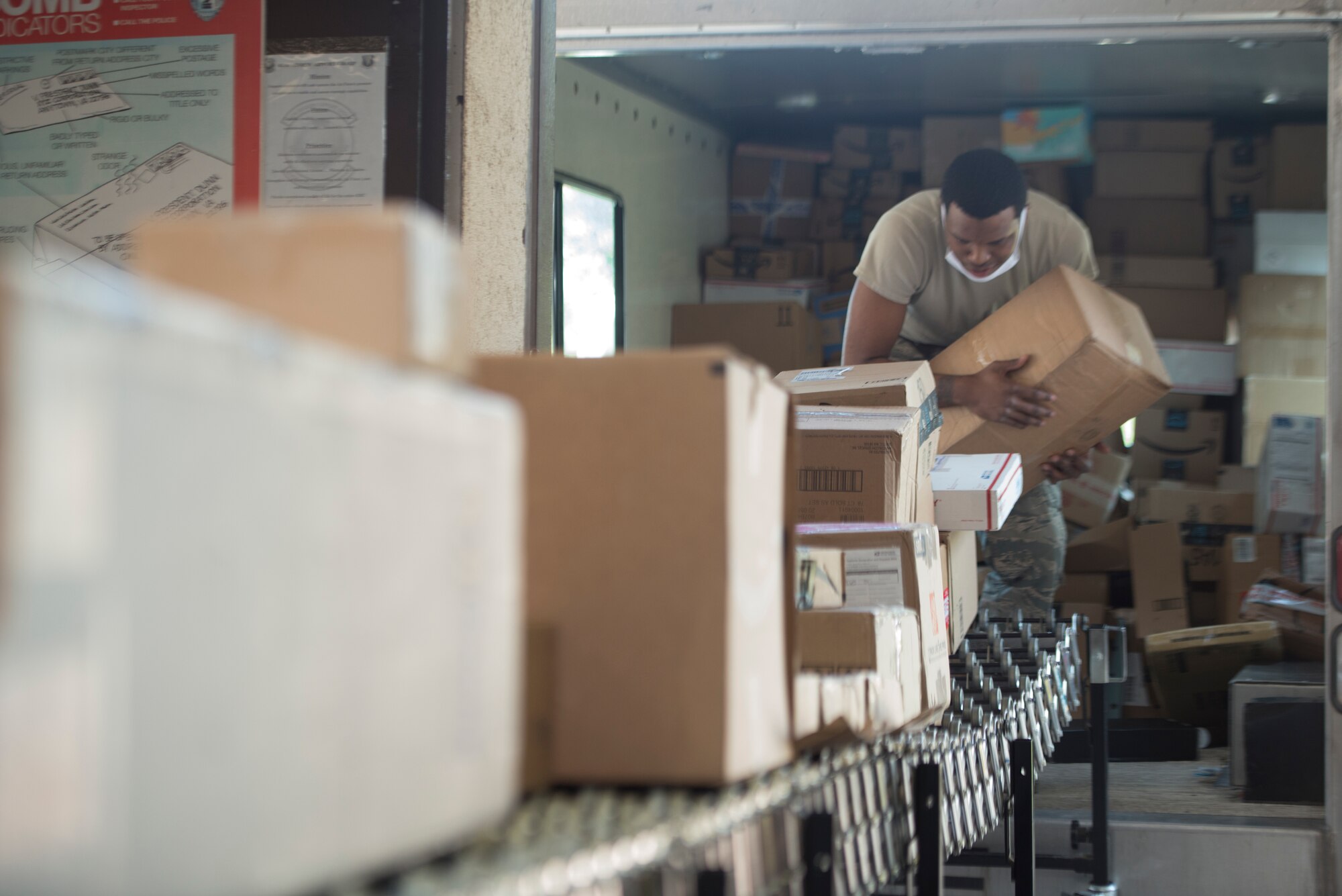 A photo of an Airmen placing packages on a conveyor belt.