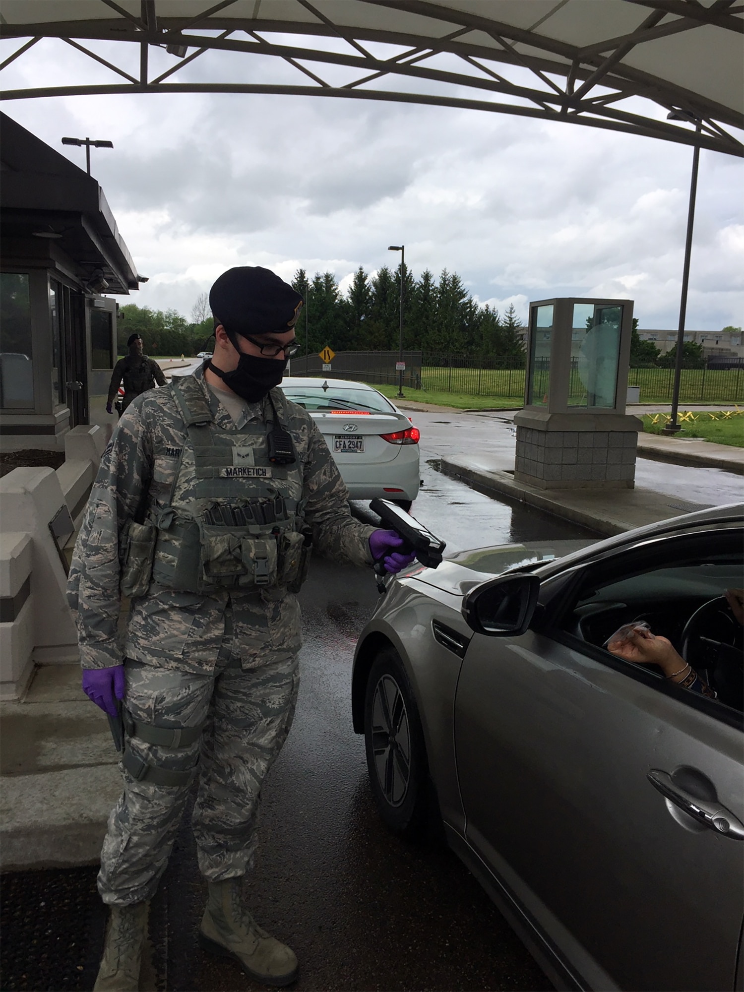 Senior Airman Aaron Marketich, 88th Security Forces Squadron, demonstrates the mask and gloves he and fellow defenders are utilizing during the COVID-19 situation on May 18 at Wright-Patterson Air Force Base’s Gate 12A.
