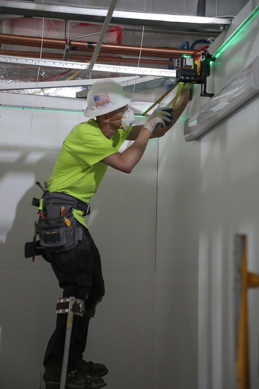 A contractor eyes the levelness of his work installing lights May 19, on the framework for the pods of what will be an alternate care facility in the fight against the Covid-19 pandemic in Kalispell, Mont. The state of Montana requested FEMA to task the U.S. Army Corps of Engineers, Omaha District, to build the ACF on the vacant, undeveloped, third floor of Montana Children’s, the new pediatric facility of the Kalispell Regional Medical Center. The temporary facility would accommodate non-acute patients in case Montana faces an increase in COVID-19 patients in the fall. When completed, the ACF will have 98 patient care rooms, seven nurses' stations, four restrooms, three pharmacies and a medical supply storage room.