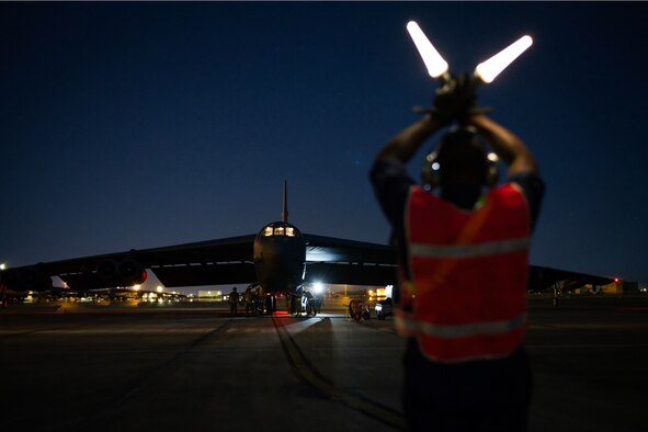Photo of Airman marshalling B-52 at night.