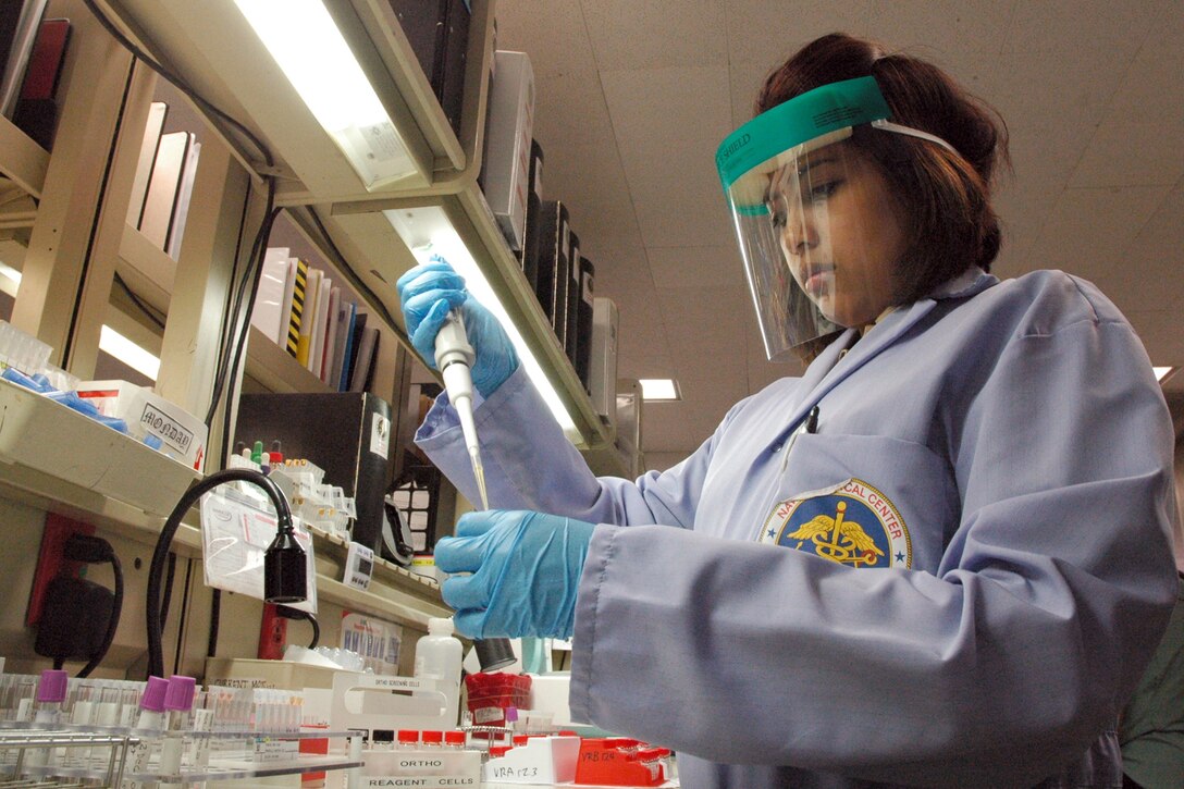 A scientist wearing PPE conducts a test.