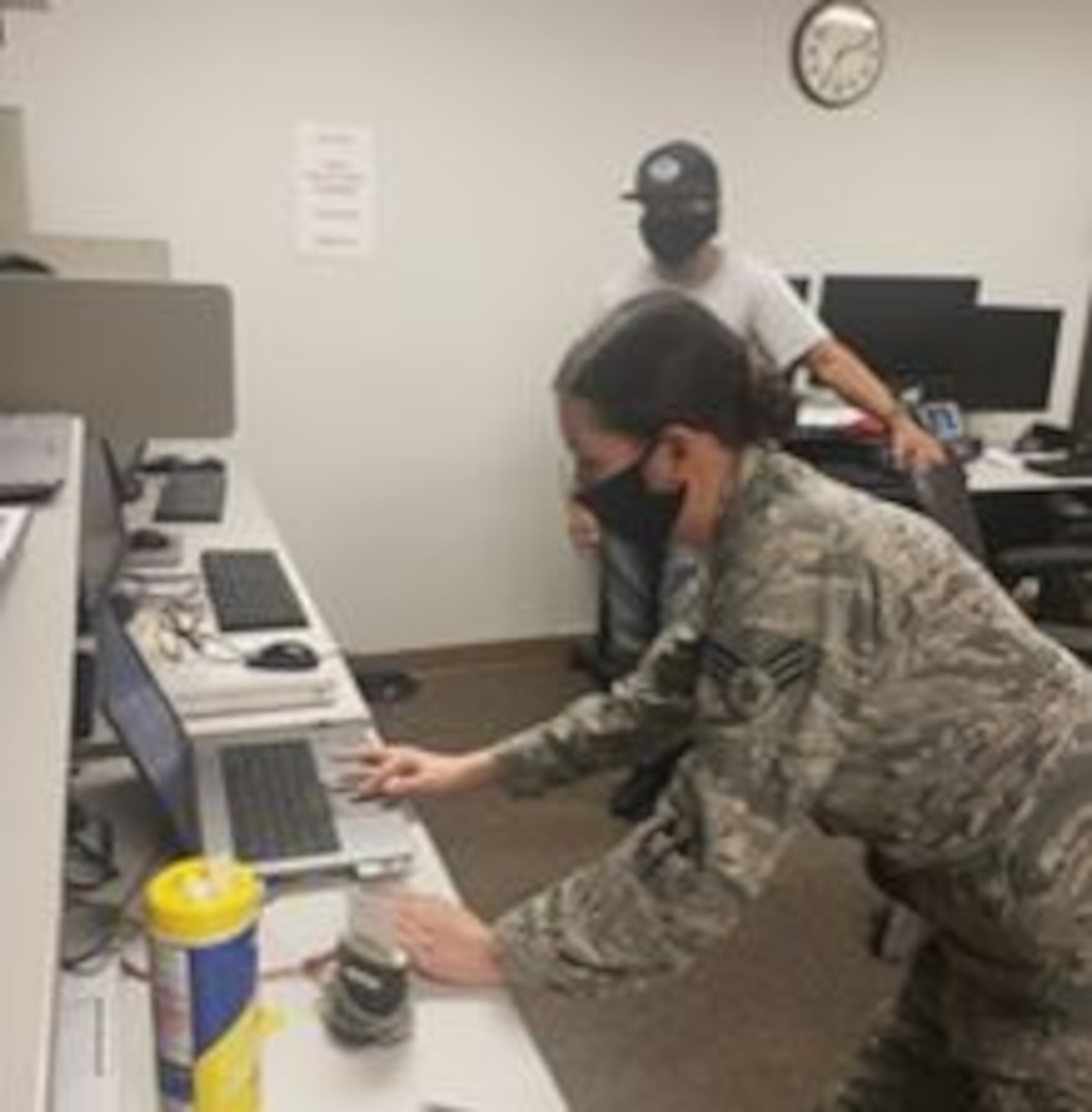 Senior Airman May Mclinden, 452nd Communications Squadron, Communications Focal Point section, does touch maintenance to patch a computer issue that prevents Tech. Sgt. Jose Mora, 452nd Maintenance Squadron, from telecommuting during the COVID-19 pandemic.