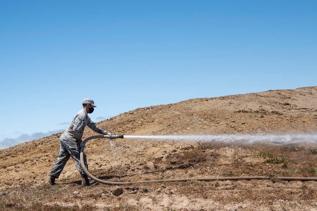 Senior Airman Amonte Anthony, 30th Civil Engineer Squadron dirt boy, sprays down dirt on top of a bunker May 28, 2020, at Vandenberg Air Force Base, Calif. During COVID-19, the 30th CES has taken measures to minimize the spread of COVID-19, such as adding automatic hand dryers and towel dispensers to bathrooms, while continuing to complete everyday work orders. (U.S. Air Force photo by Senior Airman Hanah Abercrombie)