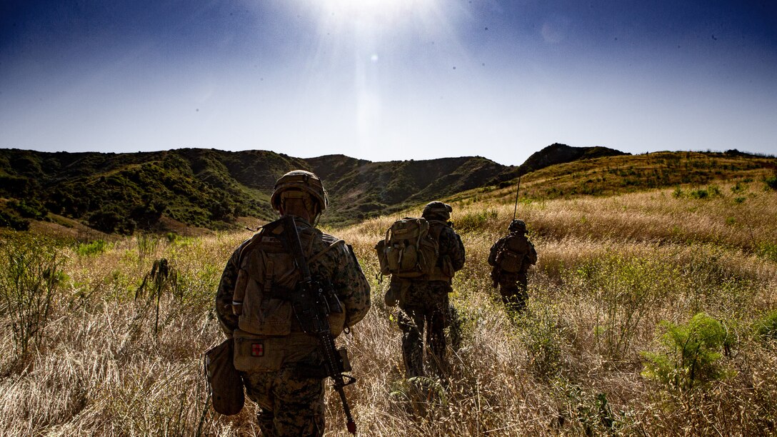 U.S. Sailors and a U.S. Marine with Charlie Company, Battalion Landing Team 1/4, 15th Marine Expeditionary Unit, walk to a landing zone during a helicopter raid course on Marine Corps Base Camp Pendleton, California, May 20, 2020. Marines focused on tactics, techniques and procedures applicable to raid operations in order to enhance their combat readiness for an upcoming deployment. (U.S. Marine Corps Photo by Cpl. Britany Rowlett)