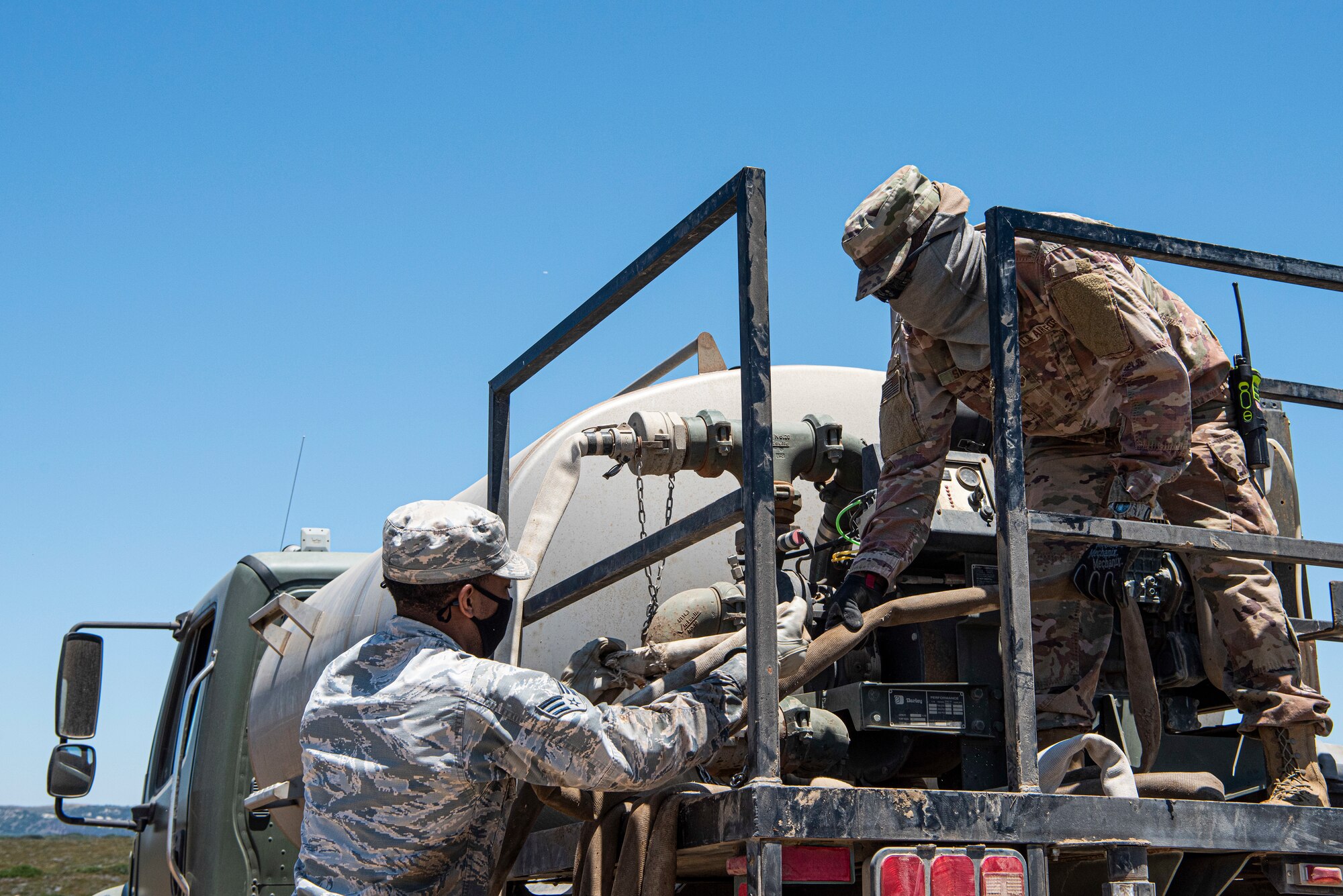 Senior Airman Amonte Anthony and Senior Airman Rashawn Simmons, 30th Civil Engineer Squadron dirt boys, wind a hose onto their truck while completing a work order May 28, 2020, at Vandenberg Air Force Base, Calif. During COVID-19, the 30th CES has taken on a higher workload, continuing to fix day-to-day work orders while making improvements across base to minimize the spread of COVID-19. To help keep members across the base safe, they have added automatic hand dryers and towel dispensers to bathrooms. (U.S. Air Force photo by Senior Airman Hanah Abercrombie)