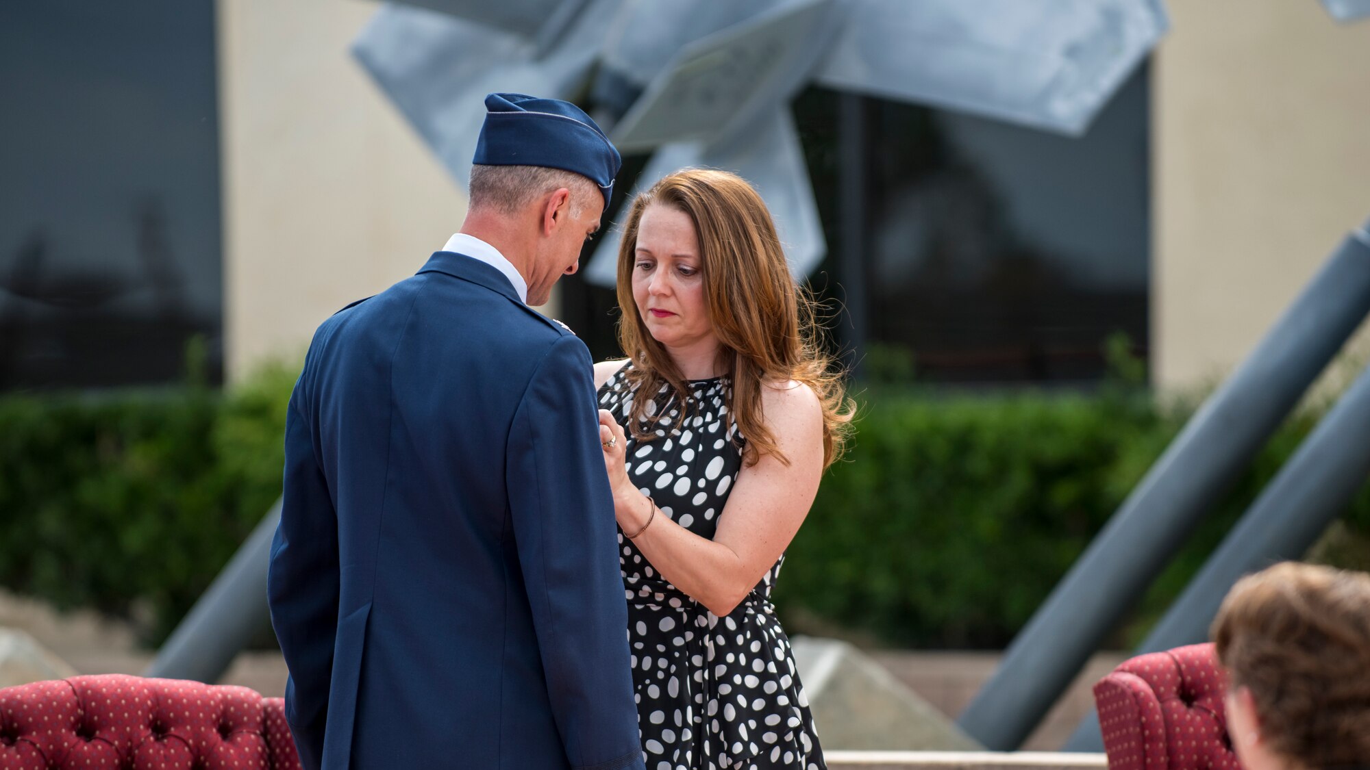 Amy Spinelli, the wife of Col. Christopher Spinelli, affixes a retirement pin on his lapel during his retirement ceremony at Edwards Air Force Base, California, May 29. (Air Force photo by Giancarlo Casem)