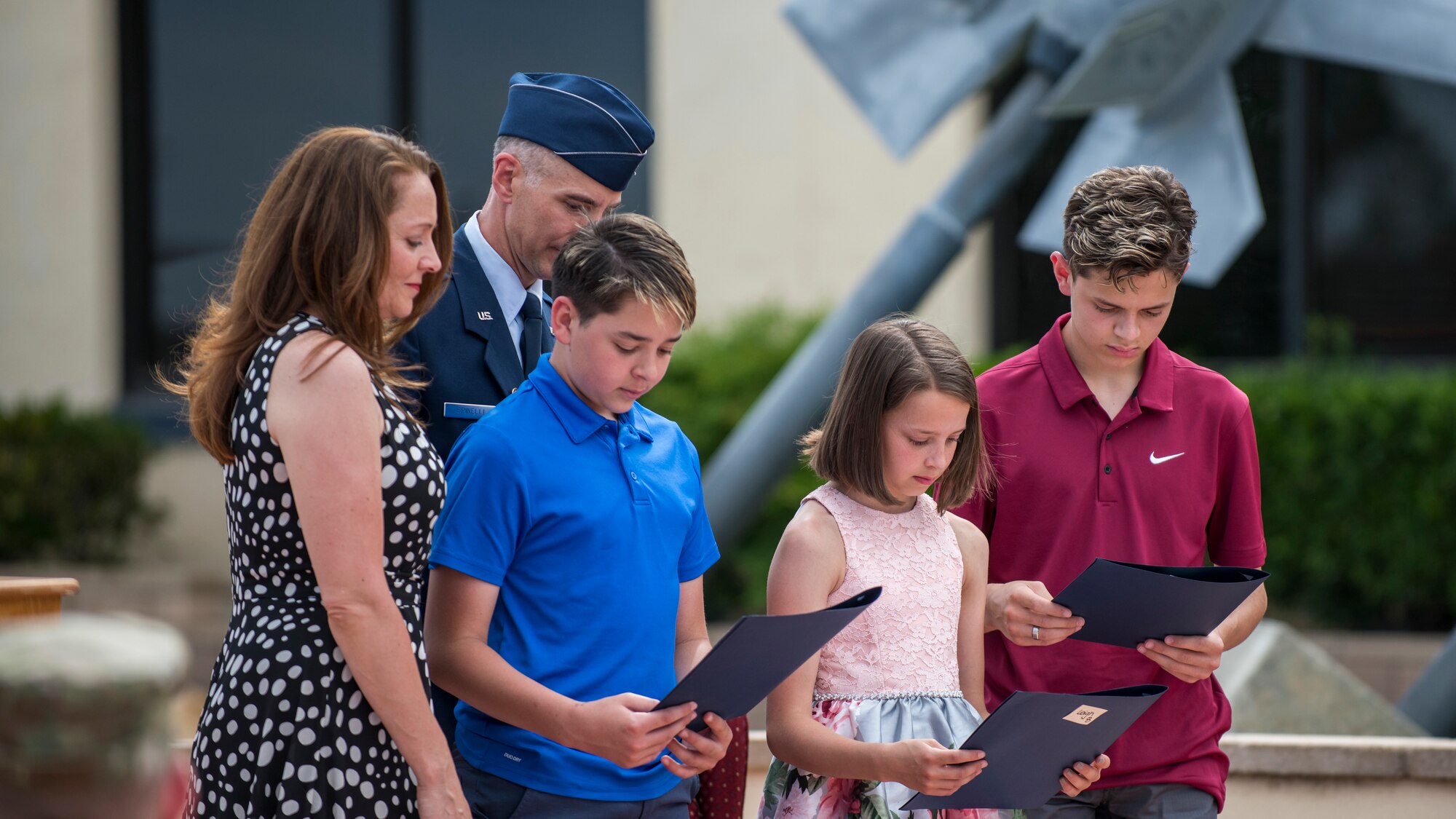 Col. Christopher Spinelli and his wife, Amy, look on as their children read thank you letters from Maj. Gen. Christopher Azzano, Air Force Test Center Commander, during Spinelli’s retirement ceremony at Edwards Air Force Base, California, May 29. (Air Force photo by Giancarlo Casem)