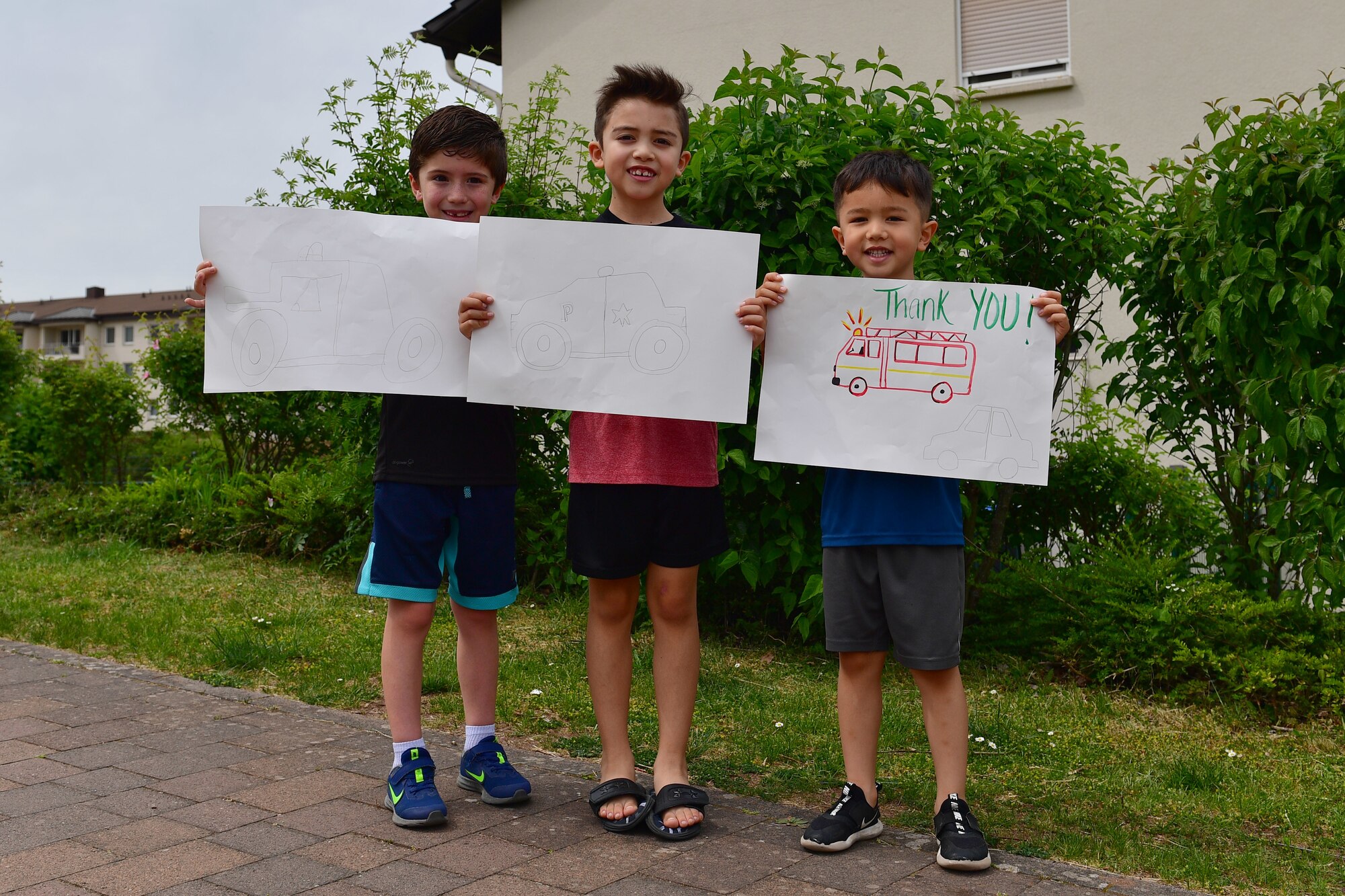 Three children hold thank you signs for first responders.