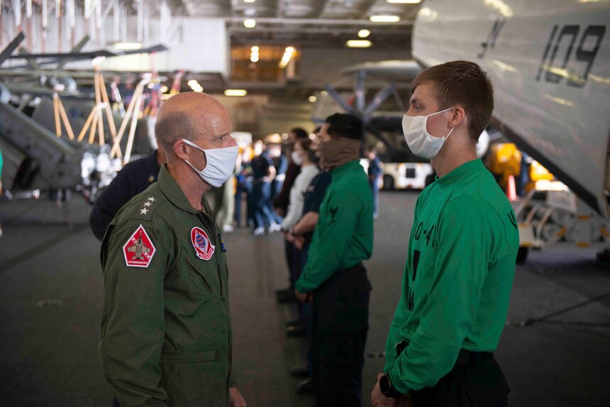 PHILIPPINE SEA (May 30, 2020) Commander, U.S. 7th Fleet, Vice Adm. William R. Merz speaks with Aviation Mechanic Airman Michael Gray from Las Vegas, assigned to Electronic Attack Squadron (VAQ) 141 in the hangar bay of the Navy’s forward-deployed aircraft carrier USS Ronald Reagan (CVN 76). During the visit, Merz talked with Sailors about the health of the force and observed the ship’s operational readiness. Ronald Reagan, the flagship of Carrier Strike Group 5, provides a combat-ready force that protects and defends the United States, as well as the collective maritime interests of its allies and partners in the Indo-Pacific region.