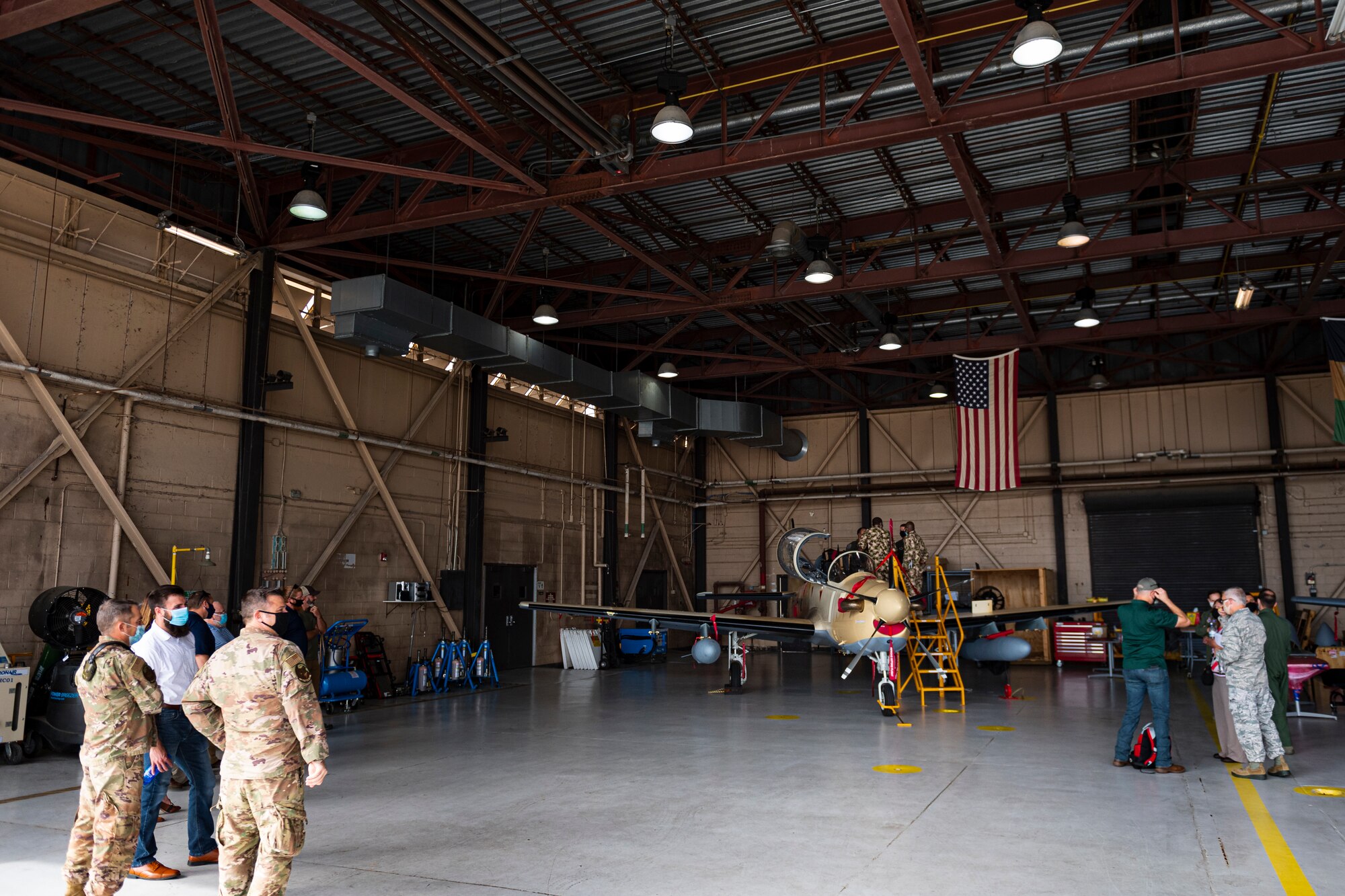A photo of participants of a squadron visit standing in a hangar