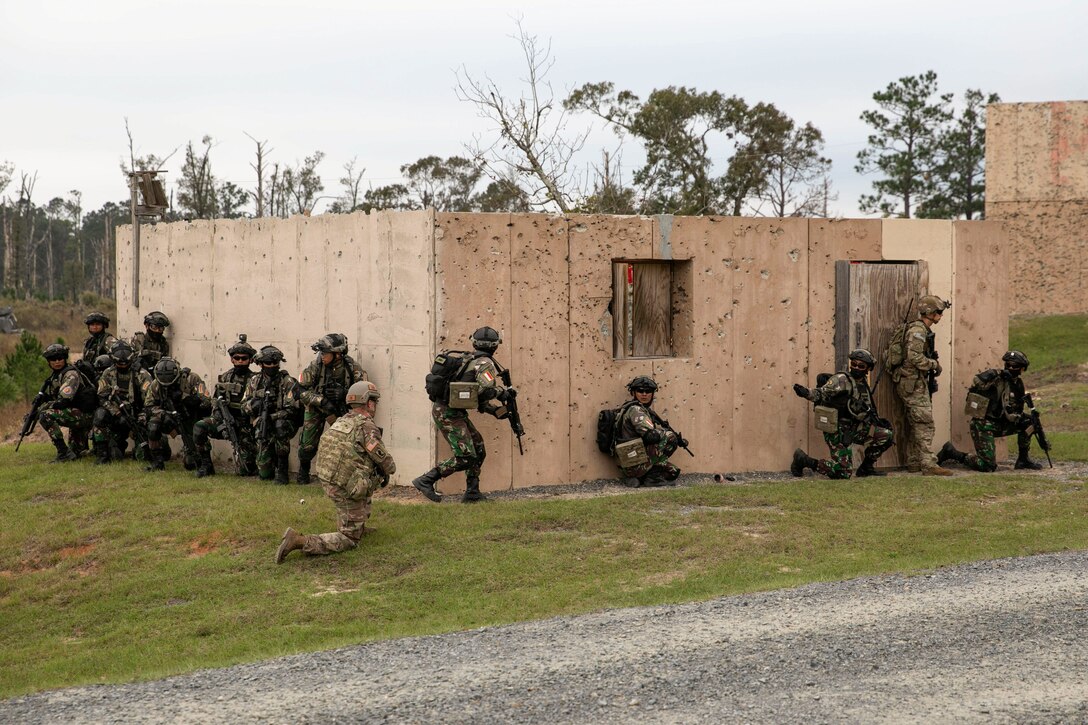 Soldiers carrying training rifles surround a building.