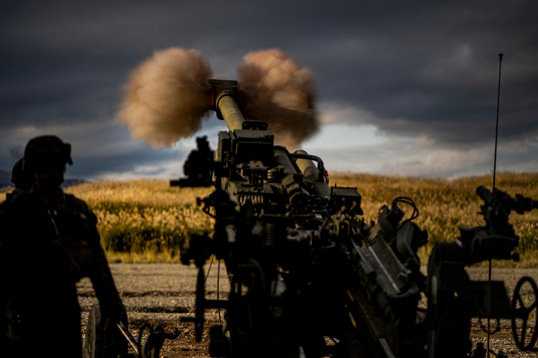 A large gun fires an artillery round.