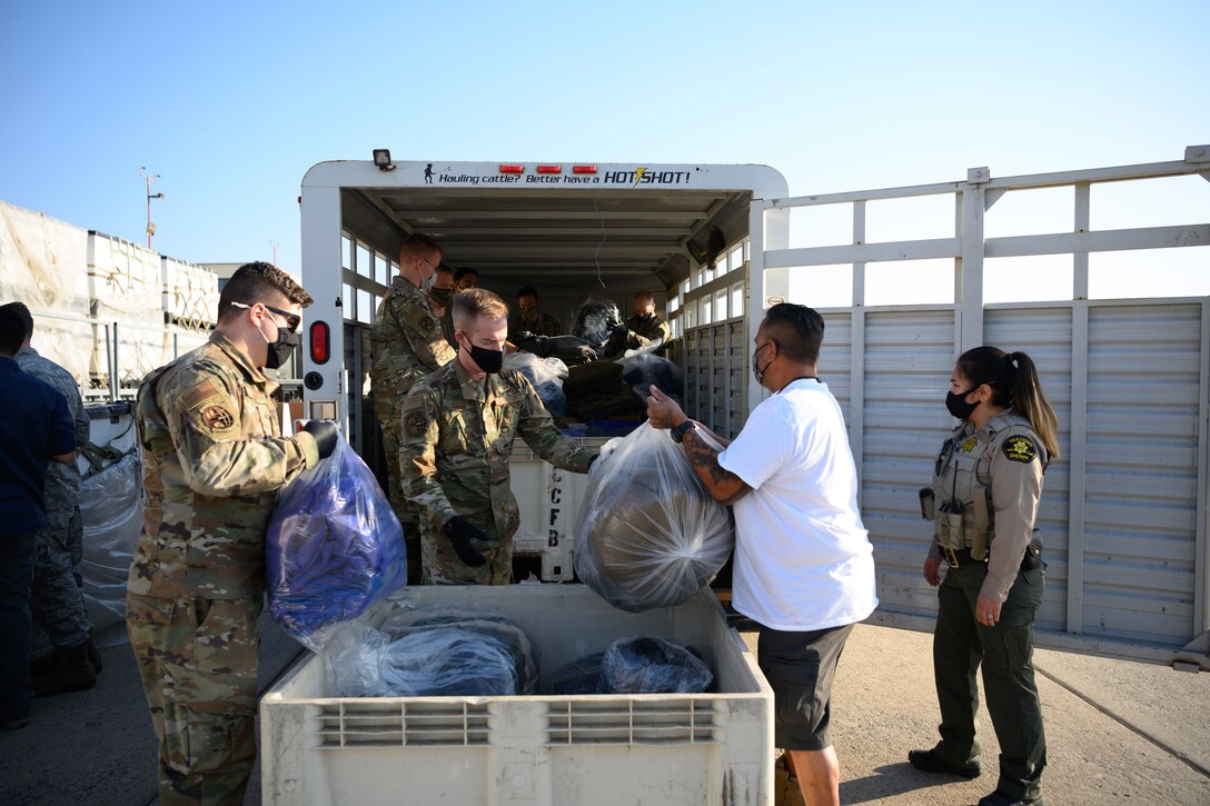 Airmen load bags of pillows and blankets into a trailer.