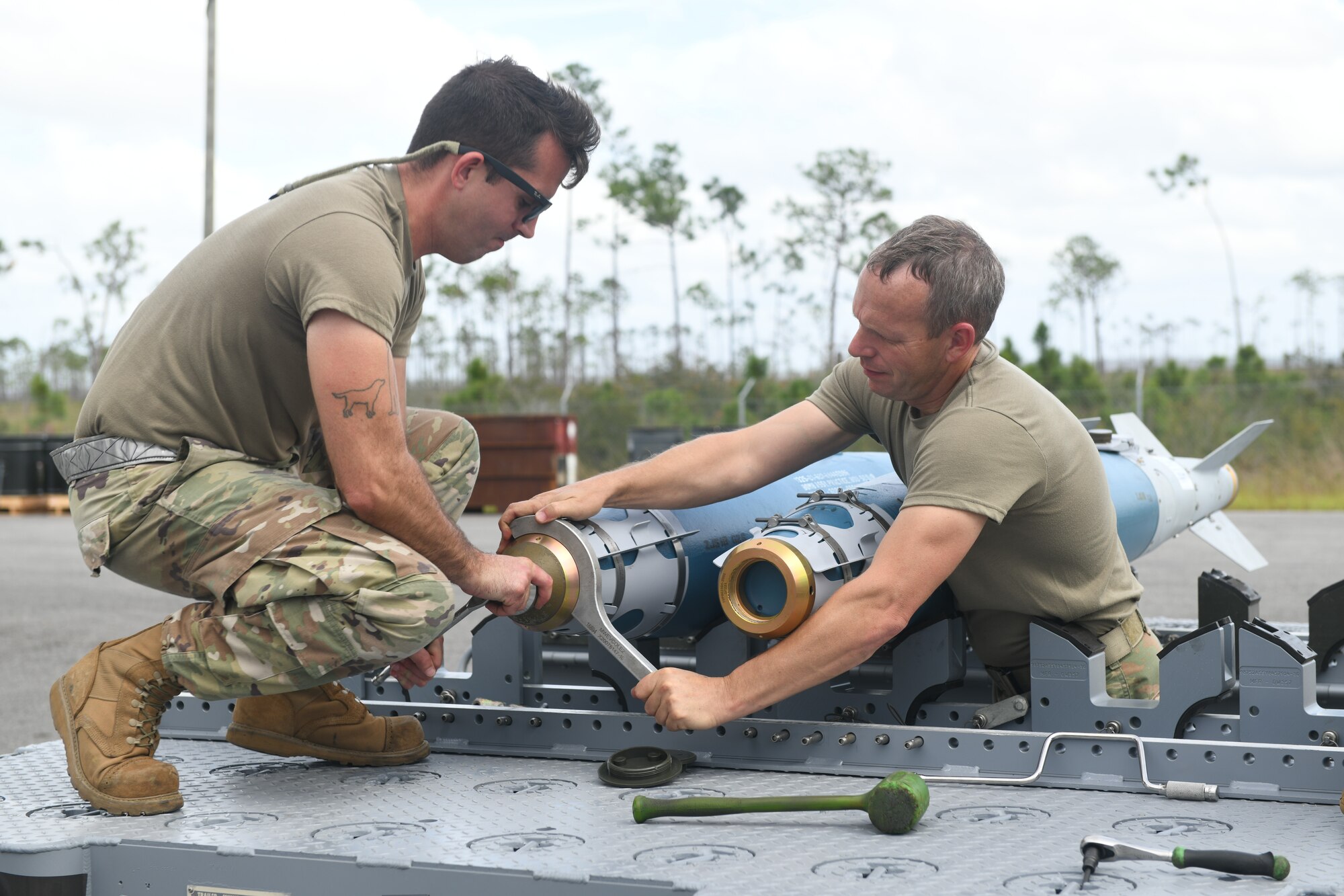 Two Airmen work to disassemble a bomb.