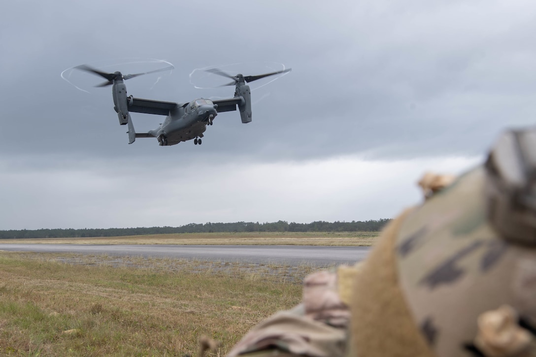 We look over the top of a Special Tactics operator's helmet as the dual-rotor helicopter comes in for a landing a couple of hundred feet away.