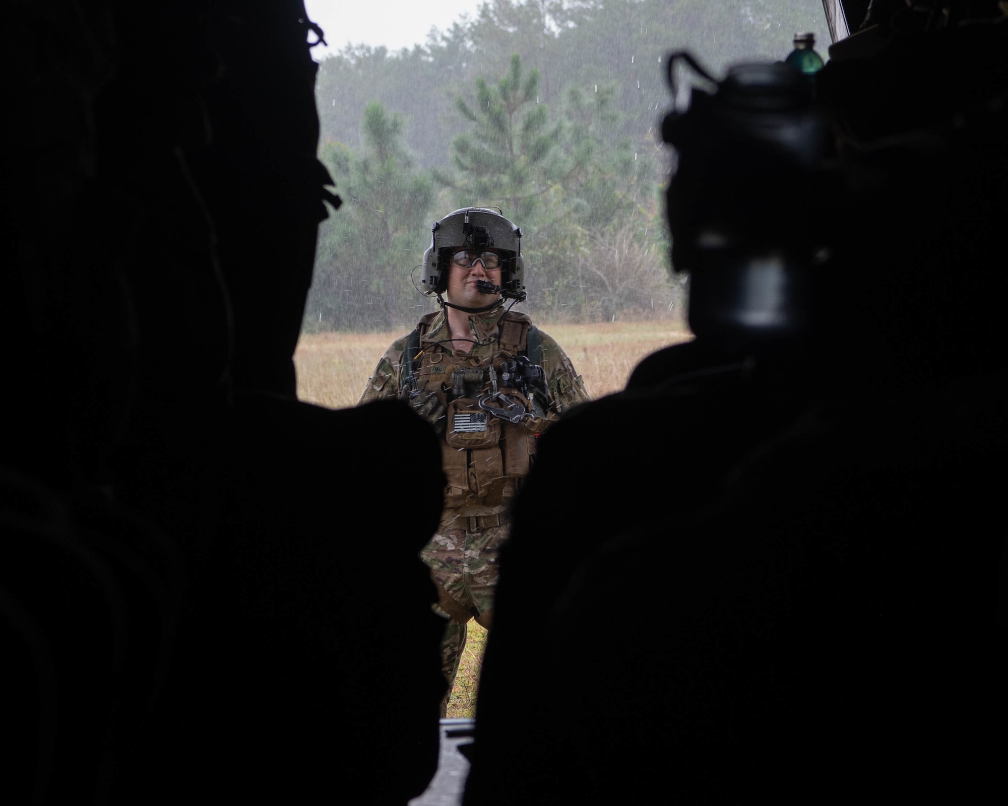 We look over the shoulders of two rows of Special Tactics operators as they look out of an open ramp of a dual-rotor operator. An operator is facing the ramp outside the helicopter making sure all Operators inside the helicopter are ready before taking off.