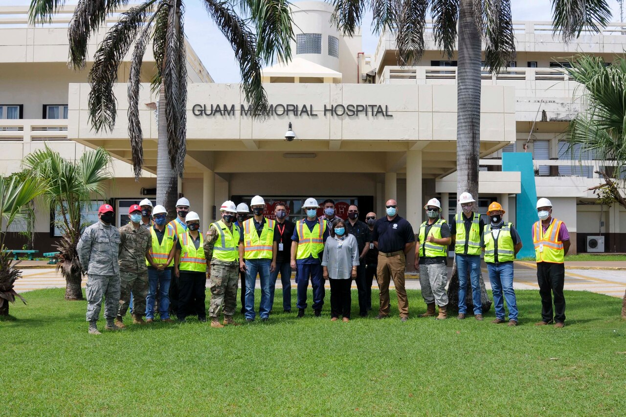 A group of federal and local workers in a group photo in front of Guam Memorial Hospital.