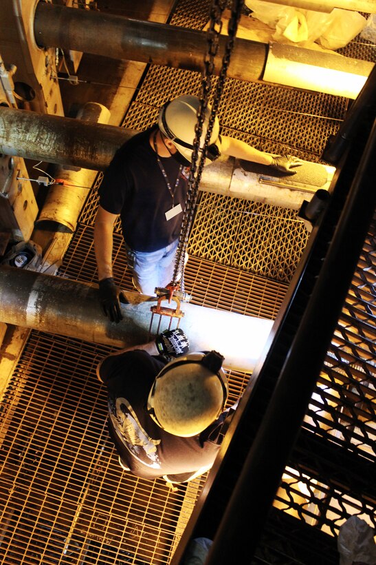 Outside machinists Todd Robison, top, and Troy Jernigan inspect a ball screw for one of the jacks on the plenum side of the nozzle of the Arnold Engineering Development Complex 16-foot supersonic wind tunnel Sept. 25, 2020, at Arnold Air Force Base, Tenn. These jacks are driven to precise locations by the nozzle motors to set correct contours for creating supersonic flow on the air side of the nozzle. (U.S. Air Force photo by Deidre Moon) (This photo has been altered by obscuring a badge for security purposes.)