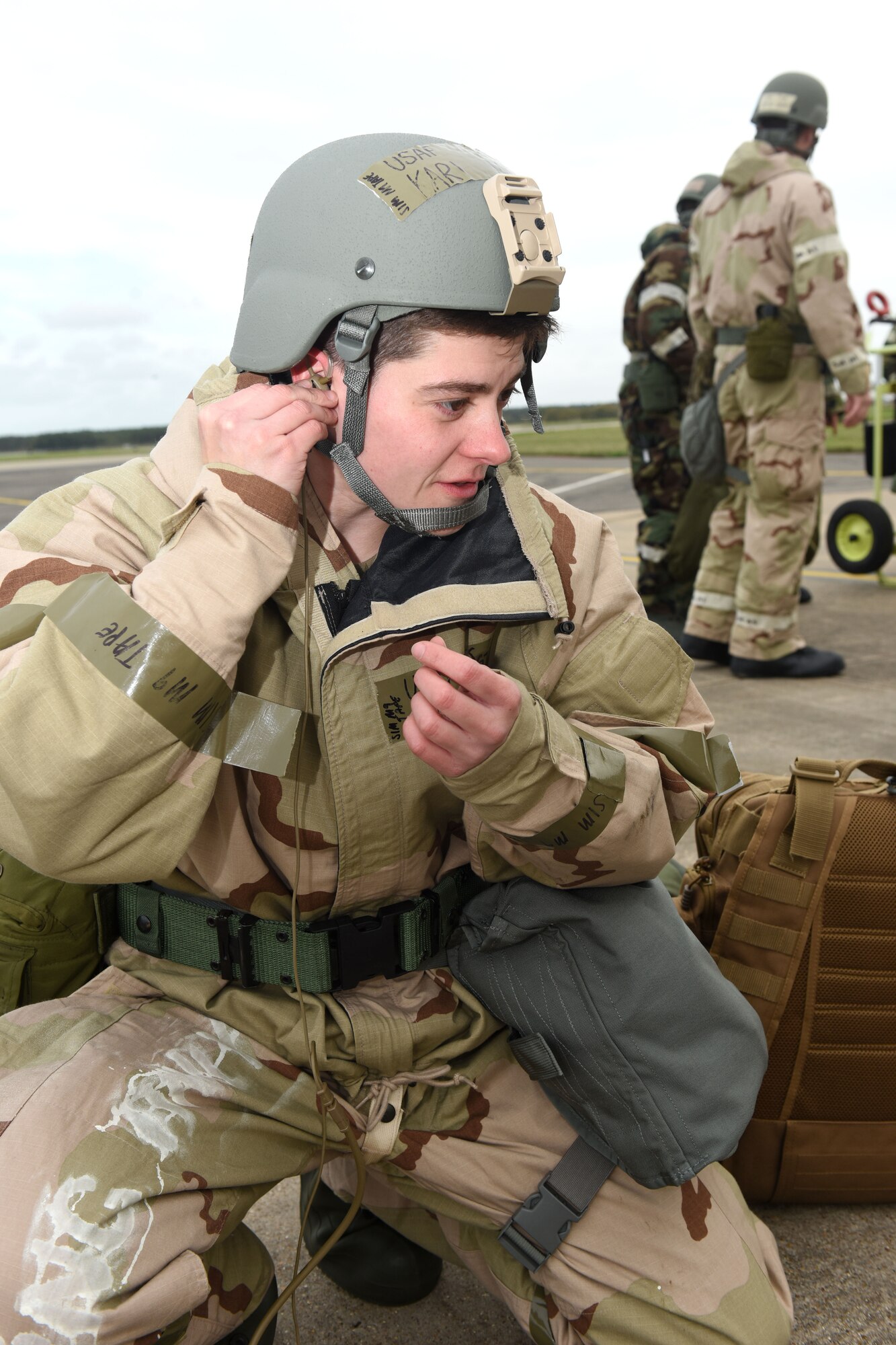 U.S. Air Force Tech. Sgt. Kari Mellott, 100th Aircraft Maintenance Squadron KC-135 Stratotanker aircraft dedicated crew chief, adjusts an in-ear headset to ensure it fits during a chemical, biological, radiological and nuclear exercise at Royal Air Force Mildenhall, England, Oct. 28, 2020. Mellott and another Airmen tested the innovative headset, which uses the bones in the user’s ear to transmit sound waves, to test its capabilities while being worn with mission-oriented protective posture gear and ensure they could communicate with aircrew in the aircraft. (U.S. Air Force photo by Karen Abeyasekere)